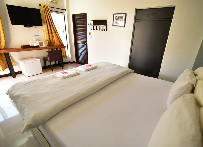 Bangrak Resort in Nakhon Sawan guest room with bed, wall-mounted TV, desk, and wardrobe
