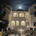 Night view of Pension George in Karterados with a lit pool courtyard and arched balconies