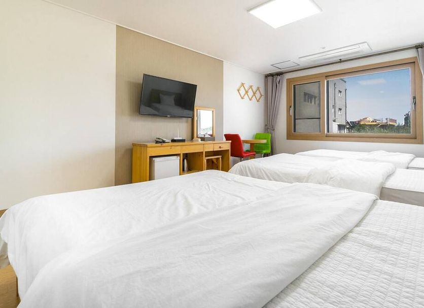 Samda Hostel Jeju City room with twin beds, wall-mounted TV, and window view