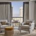 Four Seasons Hotel New Orleans suite with city skyline view, two armchairs, and a round table by tall windows