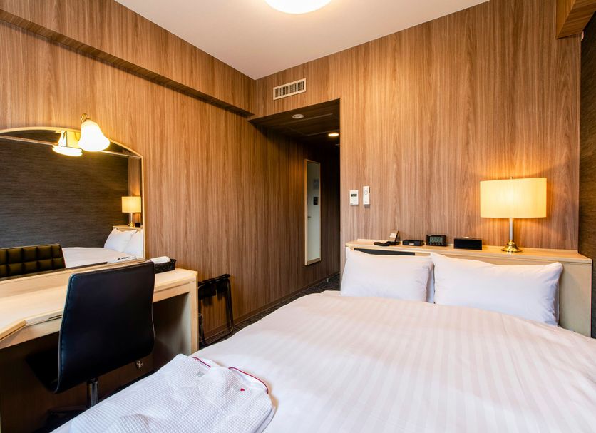Koko Hotel Asahikawa Station room in Asahikawa with bed, desk, chair and bedside lamp