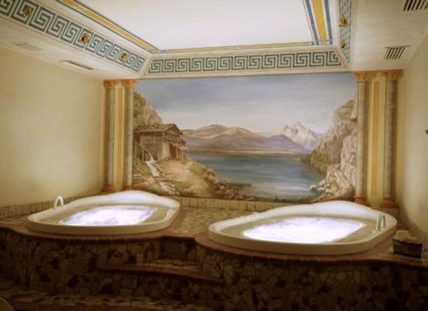 Hotel Belfiore in Monclassico spa room with two whirlpool tubs and painted mountain lake mural