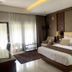The Arnawa Hotel Pangandaran guest room with king bed, sofa chair, desk and sheer curtains