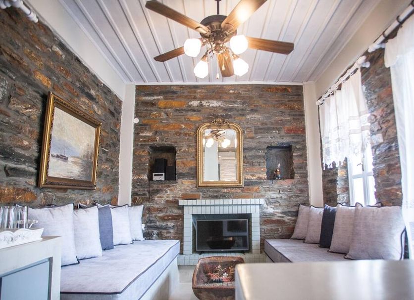 Porto Koundouros Beach And Villas lounge in Pisses with stone fireplace, sofa seating and ceiling fan