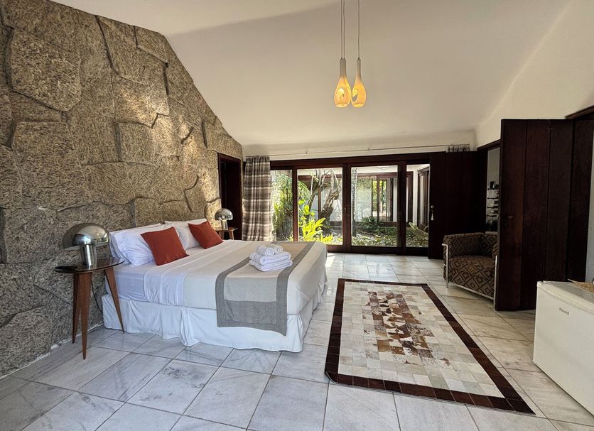Les Jardins de Rio Boutique Hotel room with stone accent wall, king bed, tiled floor and garden view