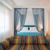 Hotel Villa Maria in Sorrento room with blue canopy bed, striped sofa, and twin beds