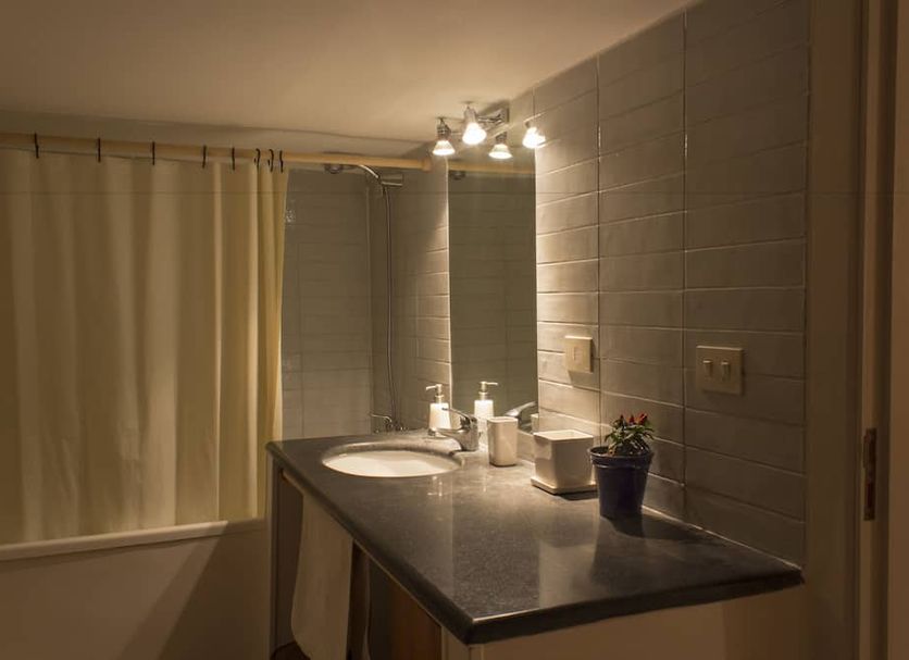 Dimora Dei Giganti in Naples: bathroom vanity with sink, mirror, tiled walls, and bathtub curtain