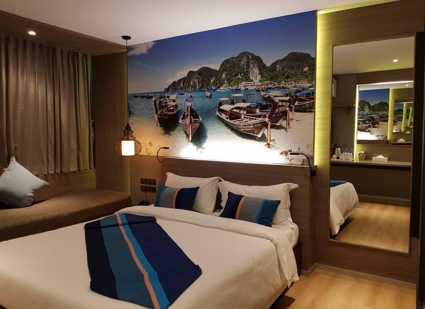 Bizotel Premier Hotel & Residence Bangkok guest room with bed, bay window seat and boat wall art