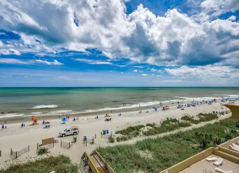 South Bay Inn Myrtle Beach beachfront view of sandy shore, ocean, umbrellas, and beachgoers