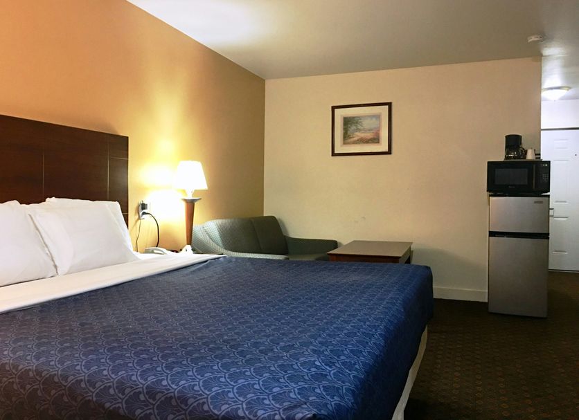 Passport Inn and Suites - Middletown guest room with king bed, sofa, lamp and mini fridge