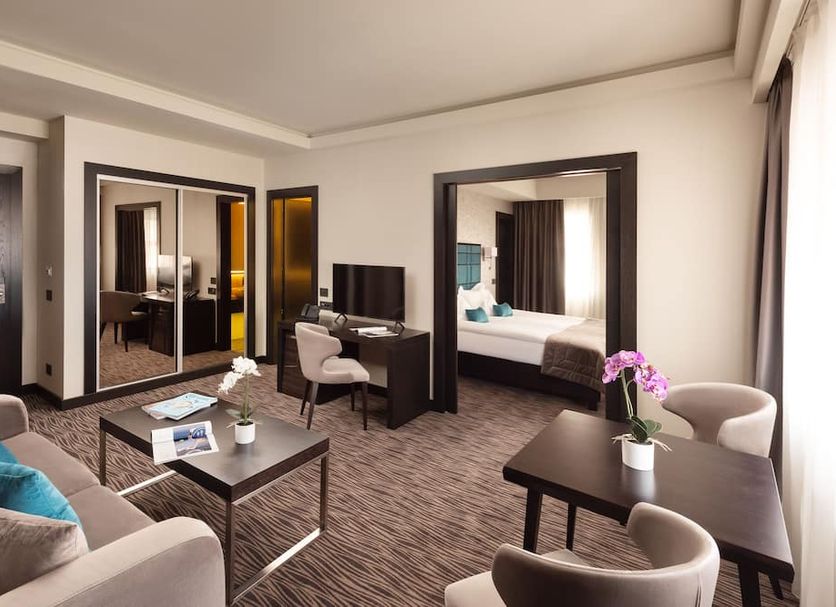 Old Town Hotel Timisoara suite with bedroom, desk, sofa seating and mirrored wardrobe