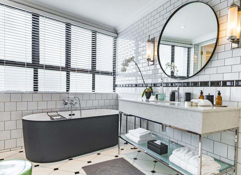 Cape Cadogan Boutique Hotel in Cape Town bathroom with freestanding tub, double vanity, round mirror and tiled walls