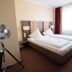 Europa Kehl Hotel guest room with double bed, bedside lamps, and a standing fan in Kehl