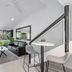 Caribbean Noosa in Noosa Heads: bright lounge with black sofa, dining nook and sliding doors to greenery