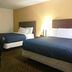 Passport Inn and Suites - Middletown room with two beds, chair, and bedside lamp