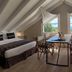 Los Ponchos Hotel in El Calafate attic room with a bed, table, and mountain view through large windows