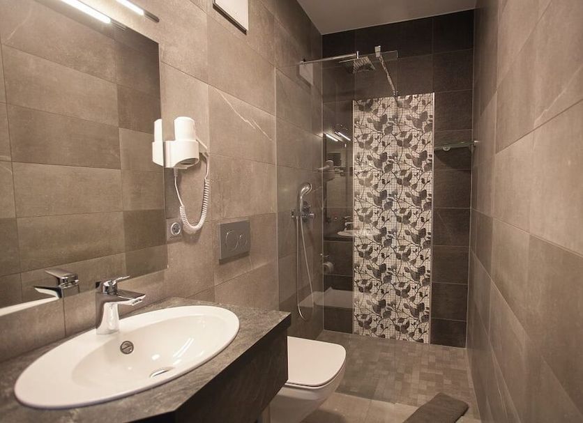 Hotel Eulensteins in Jena bathroom with sink, toilet and glass shower with floral tile accent