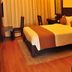 Rkn Hotel Pondicherry guest room with double bed, desk, chairs and warm wood flooring
