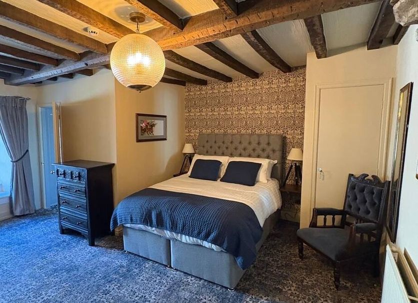 Richard III Hotel Leyburn room with king bed, exposed beams, patterned wallpaper, and window seating