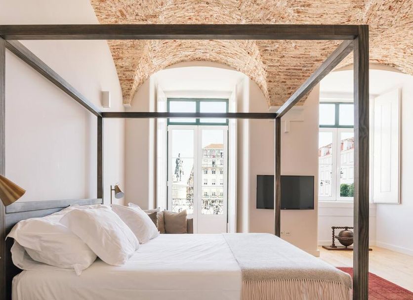 The Visionaire Apartments in Lisbon: four-poster bed beneath arched brick ceiling and tall windows