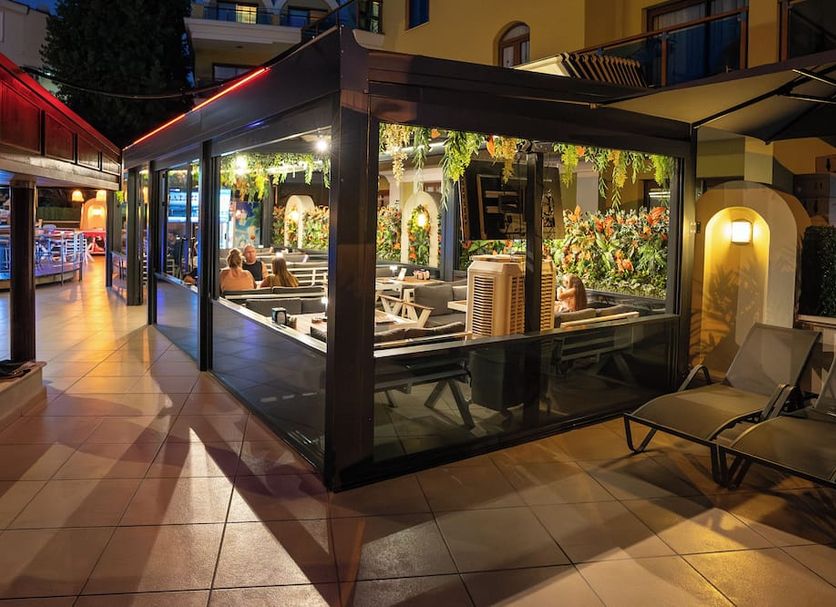 Club Karakas Apart Otel in Marmaris, glass-enclosed outdoor dining area with lounge chairs at night