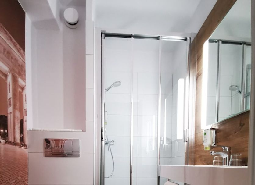 Plaza Inn Ludwigsfelde Berlin Süd bathroom with glass shower, wall-mounted toilet and wood floor