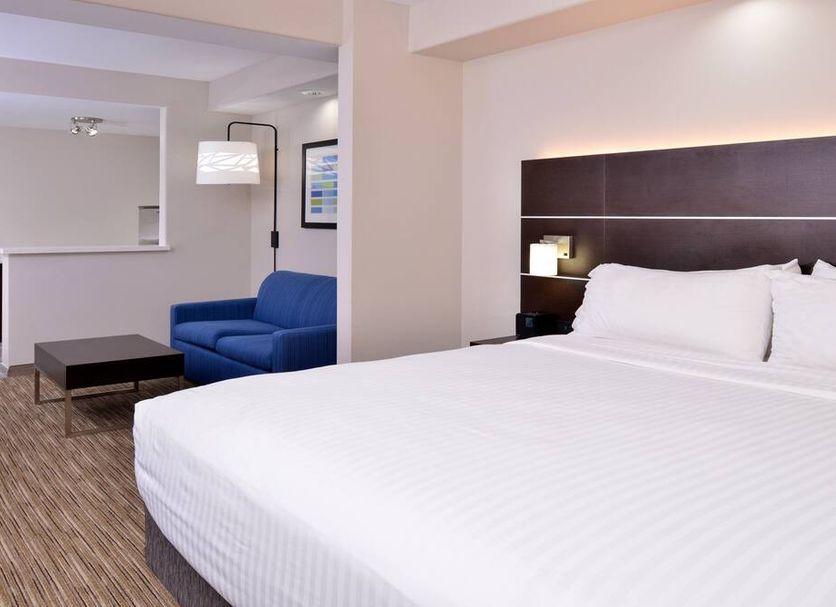Holiday Inn Express & Suites La Place By IHG guest room with king bed, blue sofa and coffee tables