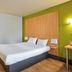 B&B HOTEL Herblay guest room with double bed, wood floors and green accent wall in Herblay