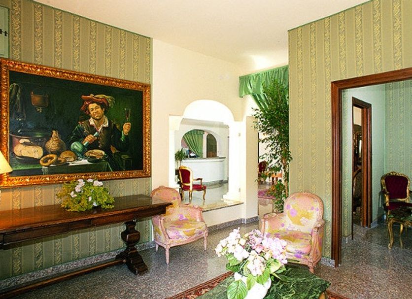 Colonna Palace Hotel Mediterraneo in Olbia lobby with vintage chairs, table and framed artwork