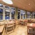 Hotel Jufa Grundlsee in Gössl dining room with large windows, wooden tables and chairs, and forest views