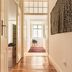 The Visionaire Apartments, Lisbon hallway with wooden floors, white walls, and a chair at the far end.