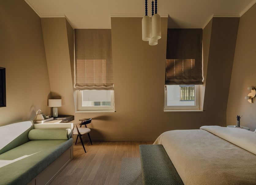 Design Hotel zum Hirschen Salzburg guest room with bed, sofa, and two windows