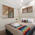 Ashmore Palms Holiday Village room with queen bed, colorful quilt, wall mirror, and windows in Ashmore