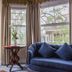 Almondy Inn Newport lounge with bay windows, beige armchair, blue sofa, and small table by the window
