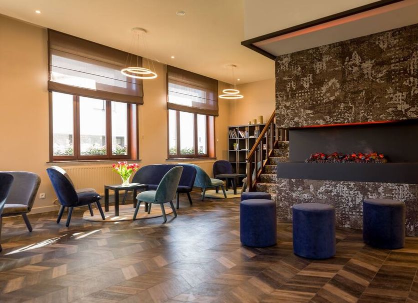 Hotel Olympia in Bruges lounge with seating, fireplace feature wall and large windows