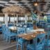 Ocean Breeze Inn Vero Beach beachfront restaurant with blue chairs and thatched umbrella tables