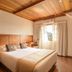 Hotel Le Renard in Campos do Jordão guest room with wood ceiling, king bed, and window view