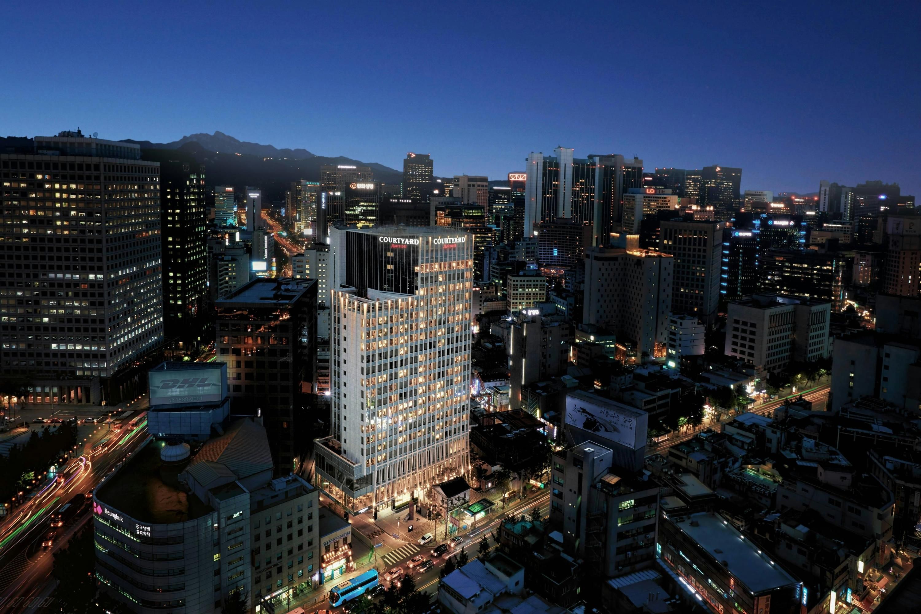 Courtyard by Marriott Seoul Myeongdong skyline view of illuminated Seoul city buildings at dusk