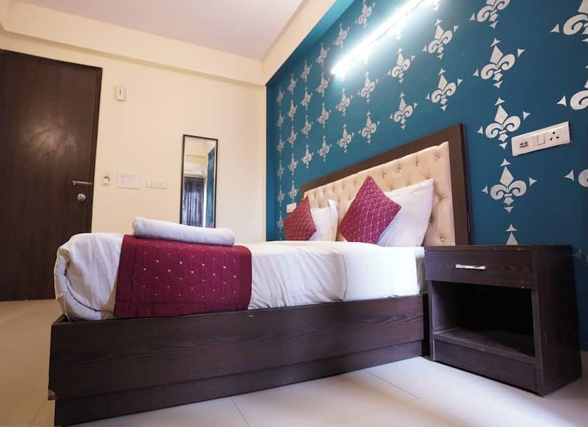 Hotel Tourist Palace New Delhi room with bed, teal patterned accent wall and bedside table