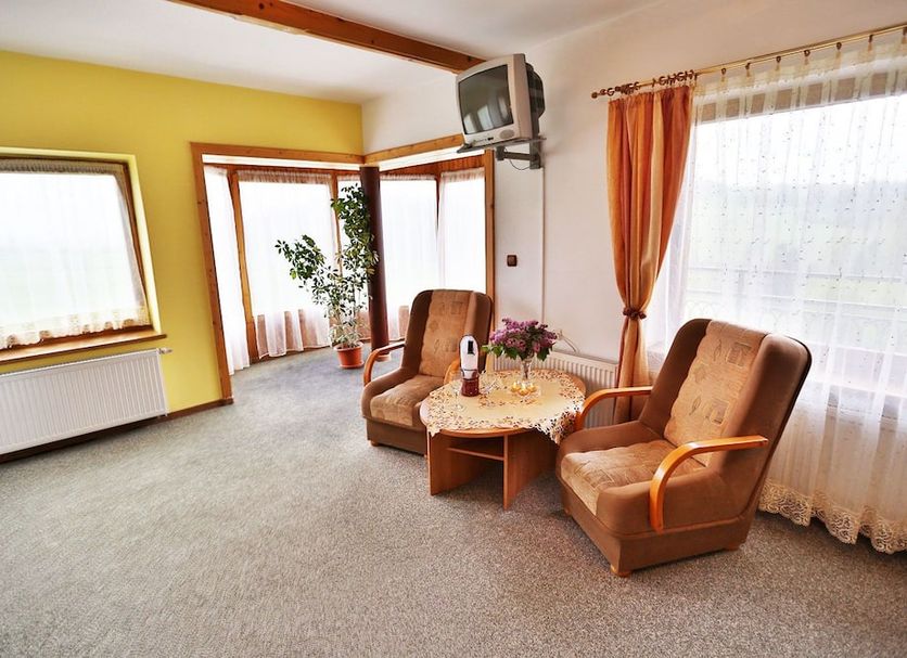 Hotel Góralski Raj in Nowy Targ living area with chairs, table, TV, and large windows