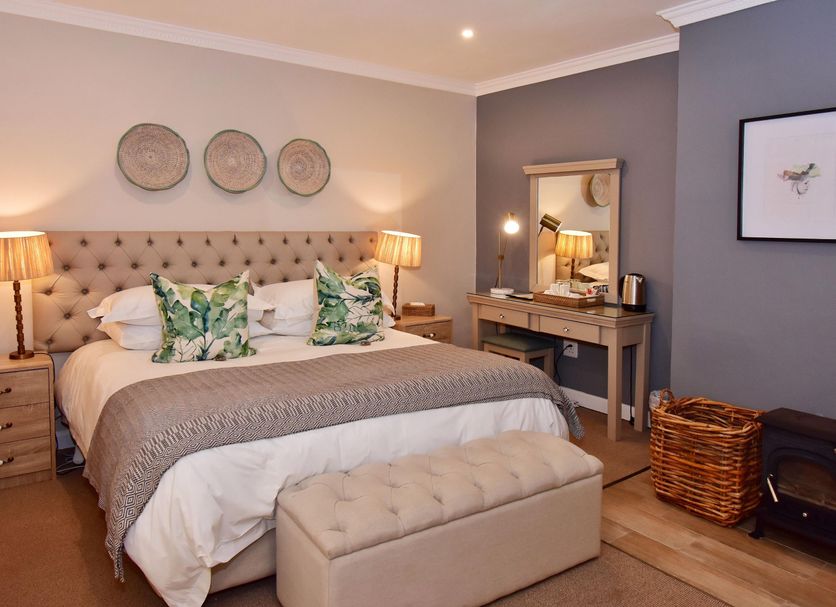Mont d'Or Hotel Clarens bedroom in Clarens with tufted bed, vanity, lamps, and bench seating