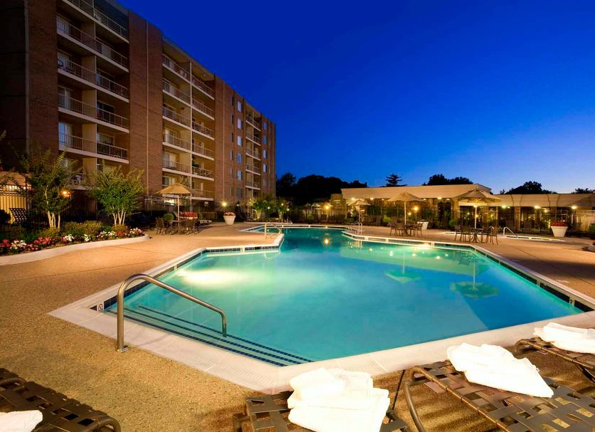 Oakwood Falls Church outdoor pool at dusk with apartment-style hotel building and lounge chairs in Falls Church