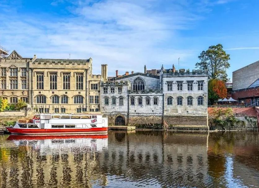 The Gillygate Pub in York with riverside buildings reflected in the water and a boat on the river