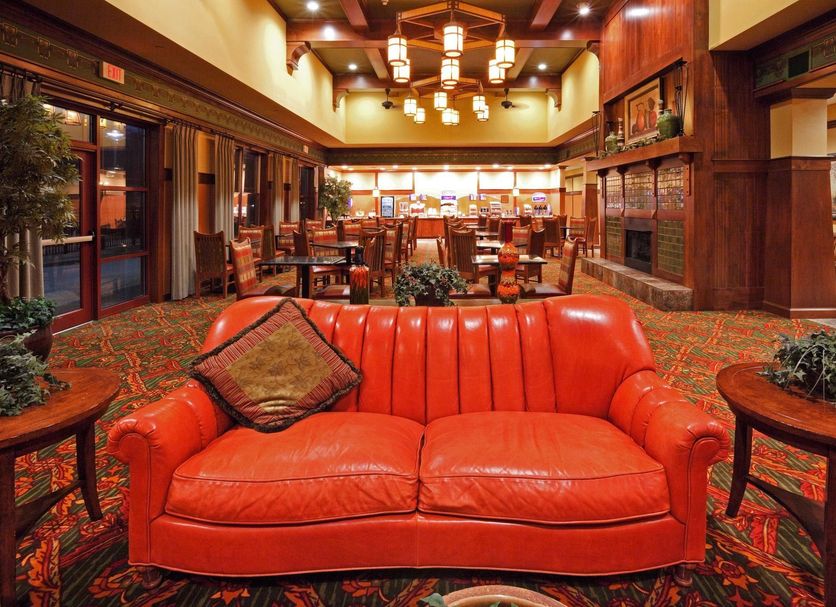 The Q Hotel & Suites Springfield lobby with red leather sofa, wood-paneled walls, and chandeliers