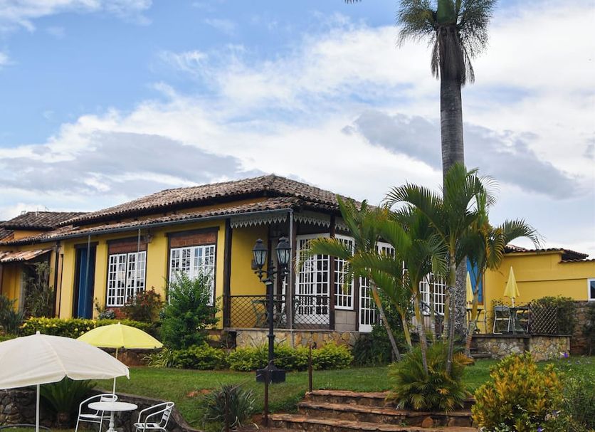 Pousada Paço do Lavradio in São João del Rei with yellow colonial buildings, palm trees, and patio umbrellas