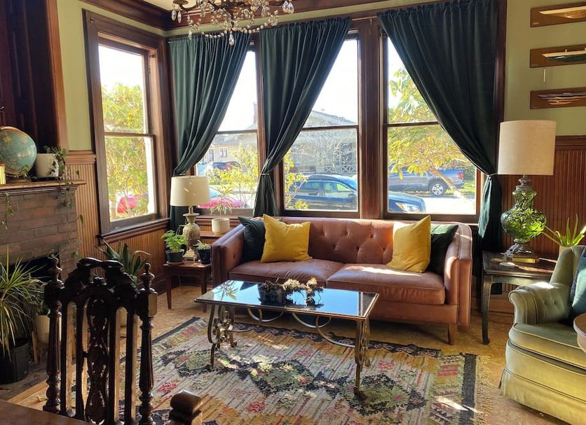 The Weller House in Fort Bragg lounge with tufted sofa, fireplace, and large windows