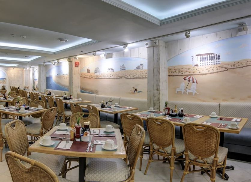 Castle in the Sand in Ocean City dining room with woven chairs, set tables, and beach mural walls
