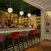 The Cura Hotel Kensington, London bar with stools, backlit shelves and framed wall art