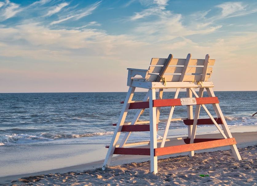 The Beach Club on Madison Avenue in Cape May with a lifeguard chair on a sandy beach by the ocean