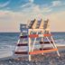 The Beach Club on Madison Avenue in Cape May with a lifeguard chair on a sandy beach by the ocean